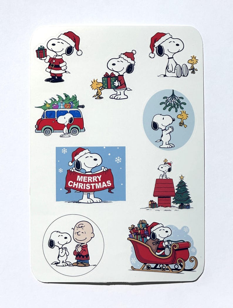 May include: A sheet of Christmas stickers featuring Snoopy and Woodstock in festive scenes. Snoopy is depicted wearing a Santa hat, delivering gifts, driving a red van with a Christmas tree, and holding a banner that reads "Merry Christmas."