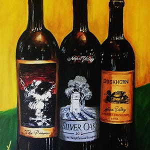 May include: Three wine bottles with labels. The left bottle has a black and white label with the text "The Prisoner". The middle bottle has a black and white label with the text "SILVER OAK 2012 Napa Valley Cabernet Sauvignon". The right bottle has a gold label with the text "DUCKHORN VINEYARDS Napa Valley CABERNET SAUVIGNON 2012".