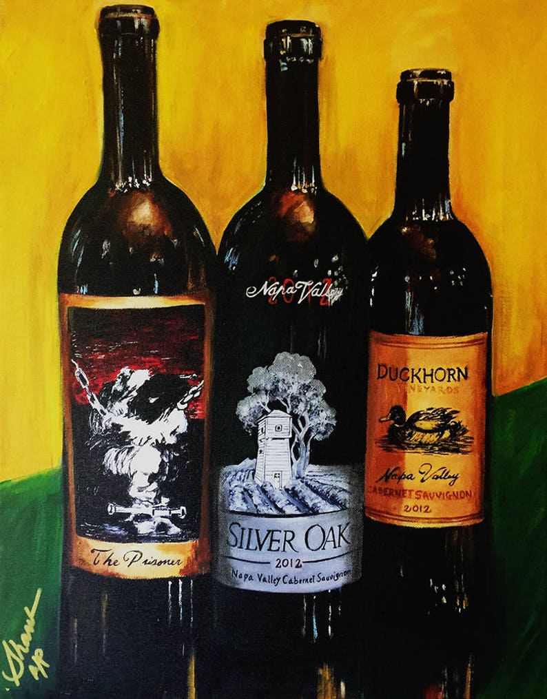 May include: Three wine bottles with labels. The left bottle has a black and white label with the text "The Prisoner". The middle bottle has a black and white label with the text "SILVER OAK 2012 Napa Valley Cabernet Sauvignon". The right bottle has a gold label with the text "DUCKHORN VINEYARDS Napa Valley CABERNET SAUVIGNON 2012".