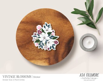 May include: A sticker featuring a bouquet of white and pink flowers with burgundy accents. The flowers are arranged in a circular shape and have a vintage aesthetic. The sticker is labeled "Vintage Blossoms" and measures 2.75x3 inches.