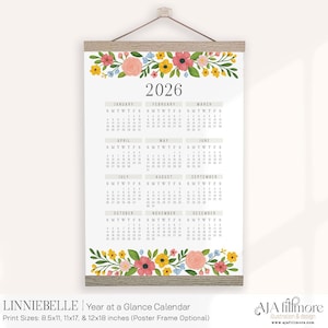 May include: A 2026 year-at-a-glance calendar with a floral design. The calendar is printed on a white background and features a wooden frame. The top and bottom of the calendar are decorated with colorful flowers. The text "2026" is displayed at the top.