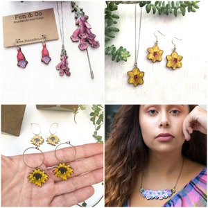 May include: A set of wooden flower earrings, a necklace, and a brooch. The earrings and necklace feature yellow daffodils, while the brooch features pink foxgloves. The jewelry is handmade and has a rustic, natural aesthetic.