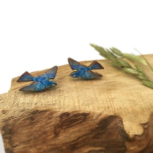 Könnte beinhalten: Ein Paar blaue Vogelohrringe aus Holz. Die Vögel sind im Flug und haben ein detailliertes Design.