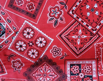 May include: Red fabric with a repeating pattern of white and black bandana designs. The fabric has a vintage look and feel.