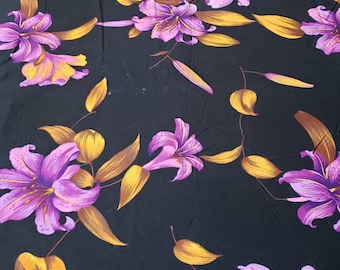 May include: Black fabric with a repeating pattern of purple and gold lilies. The lilies are stylized and have a vintage feel.