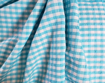 May include: A close-up of a blue and white gingham fabric with a textured surface.