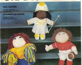 May include: A sewing pattern for doll clothes. The pattern includes three outfits: a cheerleader outfit, a football player outfit, and a marching band uniform. The pattern is for dolls that are 15 inches and 18 inches tall.
