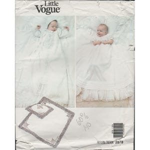 May include: A vintage Little Vogue pattern showing two babies in white christening gowns. The pattern includes a matching pillow and blanket set, all with delicate lace trim. The pattern is marked with the text "60%" and "140".