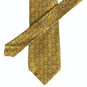 May include: Mustard yellow necktie with a repeating pattern of interlocking heart and chain designs. The pattern includes the brand's logo in a cream color. The tie is made of a smooth, shiny material.