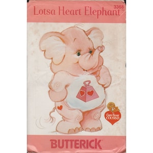 May include: A pink Care Bear Cousin elephant plush pattern with a heart-shaped tummy and the text "Lotsa Heart Elephant" and "Butterick" on the front. The pattern is for sewing a plush toy.