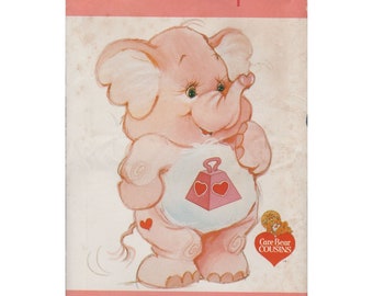 May include: A pink Care Bear Cousin elephant plush pattern with a heart-shaped tummy and the text "Lotsa Heart Elephant" and "Butterick" on the front. The pattern is for sewing a plush toy.