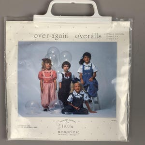 May include: A clear plastic bag containing a sewing pattern for children's overalls. The pattern features a photo of four children wearing overalls in various colours and styles. The text "over-again overalls" is visible, along with "fun wear patterns by little memories smocking designs."