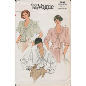 以下が含まれることがあります： サイズ14-16-18のVery Easy Vogue型紙封筒9049。イラストには、前で結ぶドレープカラーが特徴のブラウスの3つのバリエーションが描かれており、ライトグリーン、ペールピンク、ホワイトの生地で、長袖または半袖のスタイルが示されています。