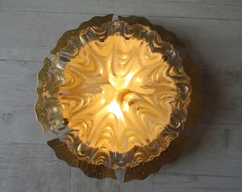 May include: A gold-toned metal wall sconce with a clear glass shade featuring a textured, wavy pattern. The light is on and illuminating the room.