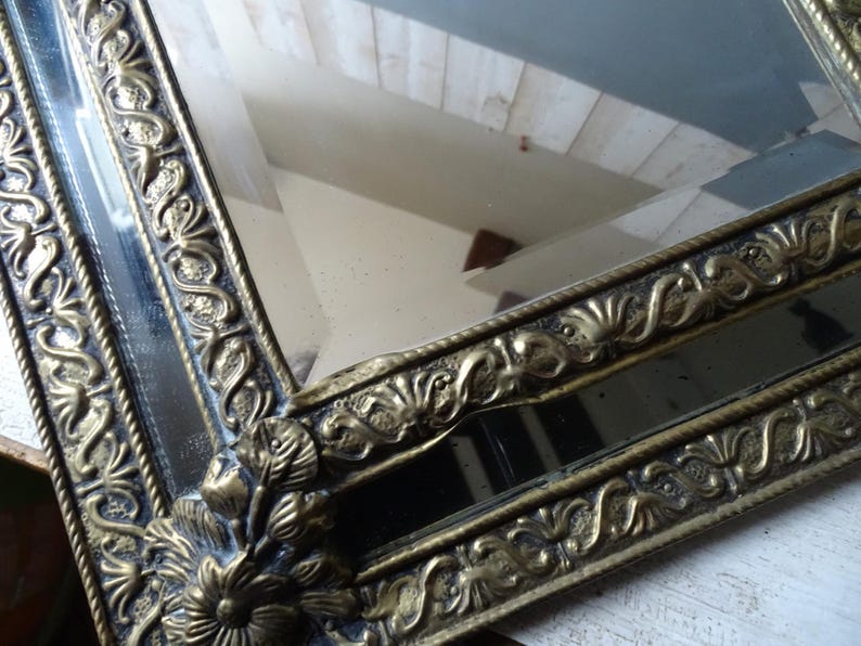 Puede incluir: Un letrero de madera r&uacute;stico blanco con la palabra "Welcome" escrita a mano. El letrero tiene un aspecto envejecido y un elemento floral decorativo. El fondo es una imagen borrosa de una casa.