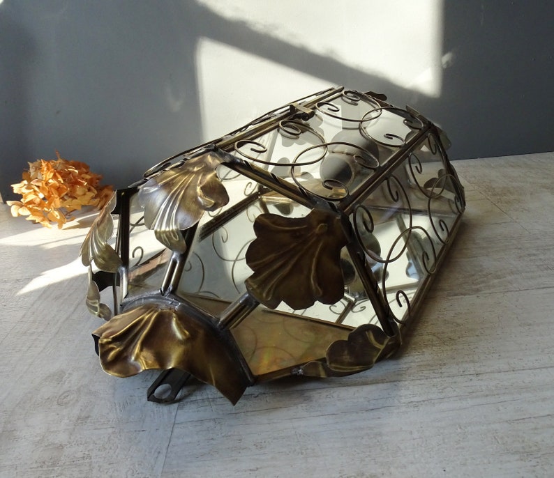 May include: A vintage glass and metal ceiling light fixture with a decorative floral design. The fixture has a clear glass shade with a metal frame and ornate details.