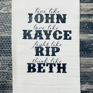 Könnte beinhalten: Weißes Küchentuch mit schwarzem Text, der lautet: "Lebe wie John, liebe wie Kayce, kämpfe wie Rip, denke wie Beth".