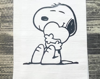 May include: A black and white illustration of Snoopy holding a heart in his arms. The illustration is printed on a white kitchen towel.