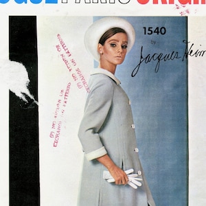 May include: A vintage Vogue Paris Original sewing pattern cover. The cover features a woman in a light blue coat, white gloves, and a matching hat. The text "VOGUE PARIS ORIGINAL" is at the top, with "1540 by Jacques Heim" below the woman's image.