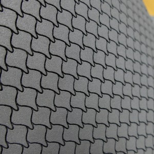 May include: Close-up of a gray textured surface with a repeating pattern of small, curved shapes. The surface has a slightly raised, embossed texture.