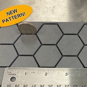May include: A gray foam material with a honeycomb pattern and a ruler showing inches. A quarter coin rests on the foam. The text "NEW PATTERN!" is in a yellow oval.