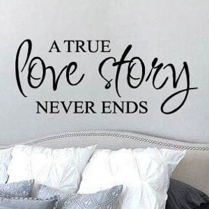 May include: A white bed with a gray and white patterned throw blanket. The headboard is gray and has a black vinyl decal that reads "A true love story never ends."