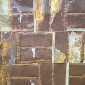 May include: A close-up of a wall covered in overlapping, rectangular panels of brown, rusty metal. The panels are weathered and have a distressed look.