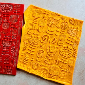 May include: Two yellow and red silicone stamps with a Scandinavian floral pattern. The stamps are textured and ready to be used for crafting projects.