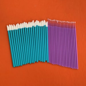 May include: Two sets of disposable applicators with white tips. One set is turquoise blue and the other is purple.
