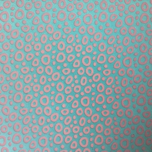 May include: A close-up of a teal fabric with a repeating pattern of pink, irregular circles. The circles are raised, creating a textured effect. The design is evenly distributed across the surface.
