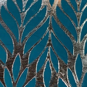 May include: A teal blue background with a silver metallic leaf pattern. The leaves are arranged in a repeating pattern, creating a decorative design.