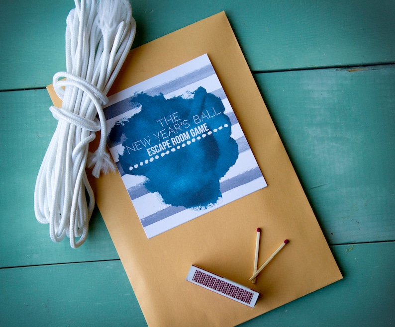 May include: A brown envelope with a white string tied around it. The envelope contains a card with the text "The New Year's Ball Escape Room Game" and a blue watercolour design. There are also two matchsticks and a matchbook inside the envelope.