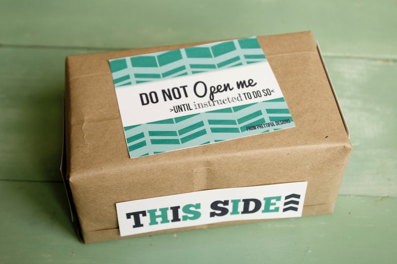May include: A brown cardboard box with a teal and white patterned sticker that says "DO NOT Open me >UNTIL instructed TO DO SO< FROM PRETTIFUL DESIGNS". A white sticker with teal lettering says "THIS SIDE" on the bottom of the box.