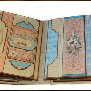 May include: Open scrapbook with multiple pages. The pages feature a mix of light blue, peach, and tan patterned paper. Decorative elements include floral illustrations, framed images of women, and the text "My Sweet Princess".