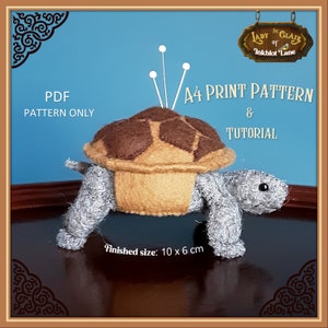 Puede incluir: Un alfiletero de fieltro en forma de tortuga con una concha marrón y un cuerpo gris. El alfiletero mide 10 cm por 6 cm y está etiquetado como "PDF PATTERN ONLY" y "A4 PRINT PATTERN & TUTORIAL".