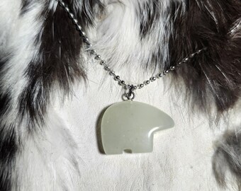 May include: A silver chain necklace with a white jade bear pendant. The pendant is carved in the shape of a bear standing on its hind legs.