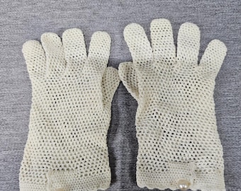May include: A pair of off-white, crocheted gloves. Each glove features a scalloped edge and a single pearl accent near the wrist. The gloves are made of a delicate, open-weave material.