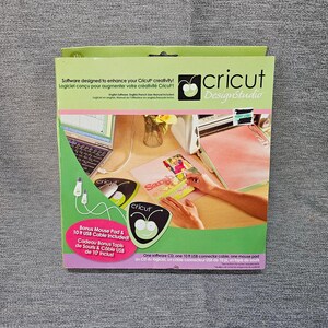 May include: A Cricut DesignStudio box with a green and white design. The box includes a mouse pad and a 10 ft USB cable. The box has text in English and French, and shows a person using the Cricut software.