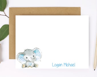 May include: A white card with a watercolor illustration of a gray elephant with blue ears and a blue heart. The text "Logan Michael" is written in blue below the elephant.