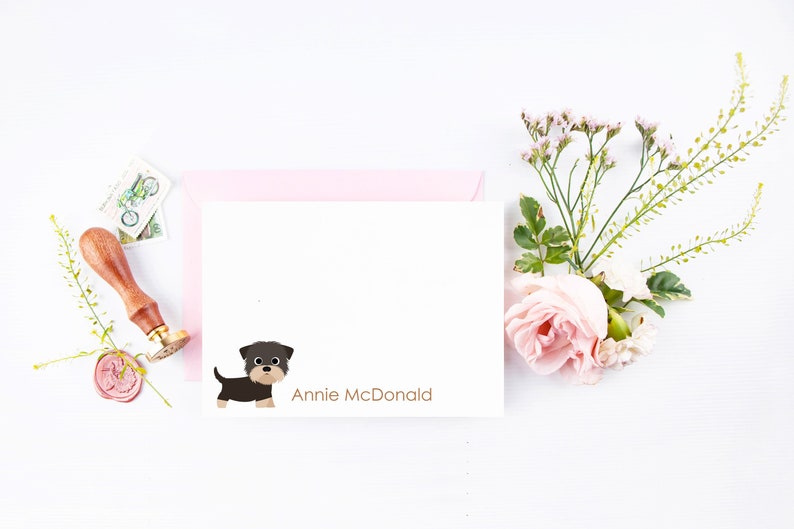 May include: A white card with a cartoon black and brown dog illustration and the text "Annie McDonald" printed in brown.