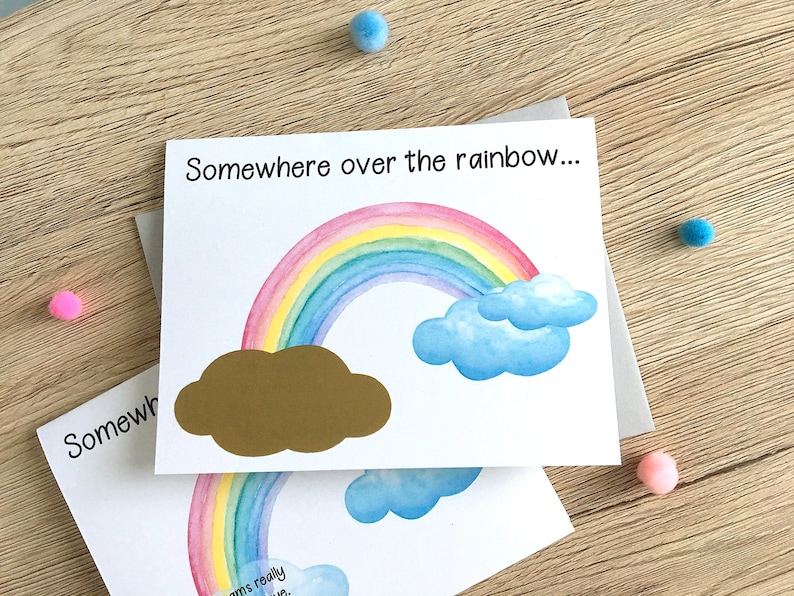 May include: A white card with the text "Somewhere over the rainbow..." printed on it. A rainbow with a gold cloud is illustrated on the card.