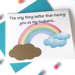 May include: A white card with a rainbow and clouds illustration. The text on the card reads "The only thing better than having you as my husband..."