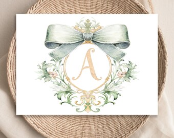 May include: A watercolor illustration of a monogram with the letter A in a gold frame, surrounded by green foliage and a large green bow.