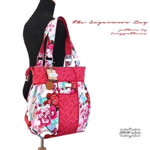 May include: A red and white floral tote bag with a geometric pattern. The bag has a zipper closure and two top handles. The bag is labeled "the Supermoon Bag" and "pattern by Imagpatterns".