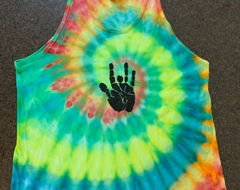 May include: A tie-dye tank top in a spiral pattern of green, yellow, blue, and orange. A black hand symbol is printed on the front. The tank top has a scoop neck and is sleeveless.