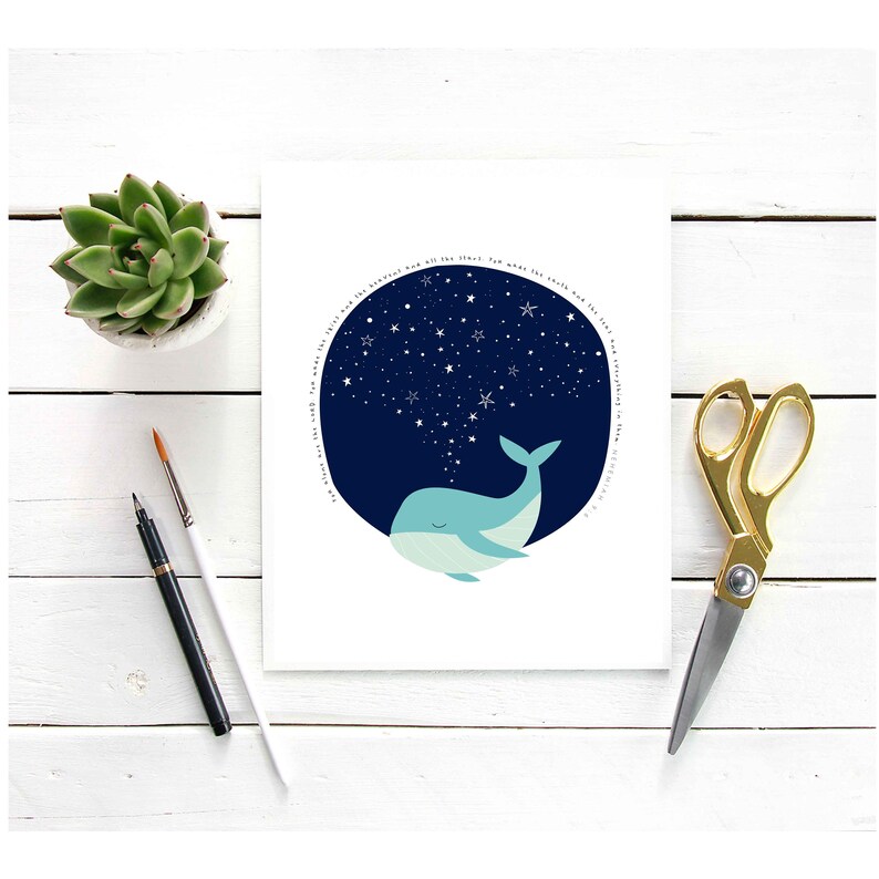 May include: A whimsical art print featuring a light blue whale with a dark blue starry sky background. The print includes the text "Silent are the world, for what the earth, and the stars". A succulent, paintbrushes, and gold scissors are also visible.
