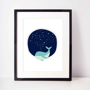May include: A framed art print featuring a whimsical illustration of a light blue whale with closed eyes, beneath a dark blue circle filled with white stars. The print includes a circular text in white.