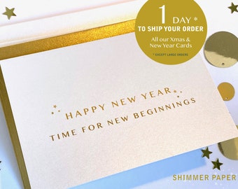 Peut inclure: Une carte blanche avec des lettres dorées en feuille qui disent "Happy New Year* Time for New Beginnings". La carte est entourée d'étoiles et de cercles dorés.