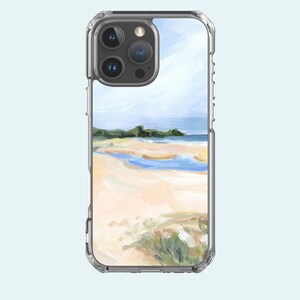 May include: A clear phone case with a painted image of a beach scene. The image features a sandy beach, blue water, and a cloudy sky.