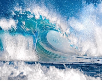 May include: A large, powerful wave crashes against the shore, creating a spray of white foam. The wave is a deep blue color, with a turquoise hue at the crest. The water is clear and blue, and the sky is a bright blue.